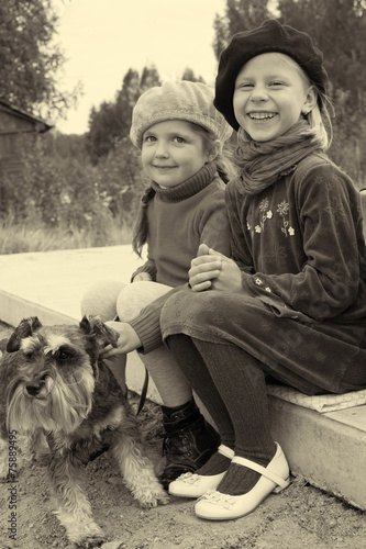 Girls tell each other secrets, sitting at the bus stop