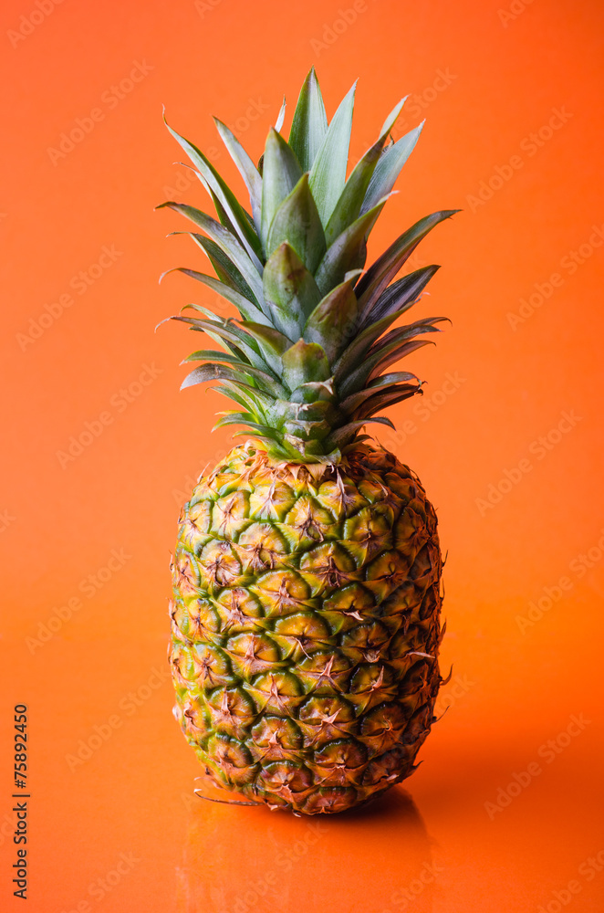 Pineapple on orange background, vertical shot Pineapple on orange background, vertical shot