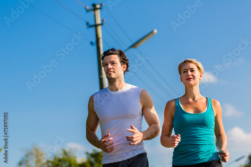 Sport couple running and jogging on rural street © Kzenon