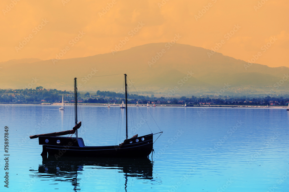 boats on a calm lake surface at sunset