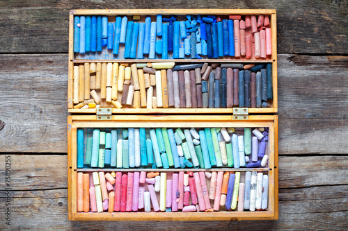 Set of multicolored pastel crayons in open wooden artist box on