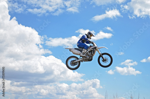 Motocross driver standing on the MX bike is flying over the
