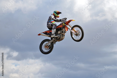 Fototapeta Naklejka Na Ścianę i Meble -  Rider by motorcycle MX flies over the hill against the blue sky
