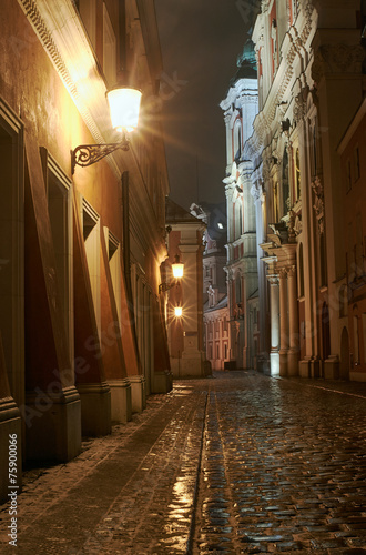 Melting snow on the cobbled street at night in Poznan.