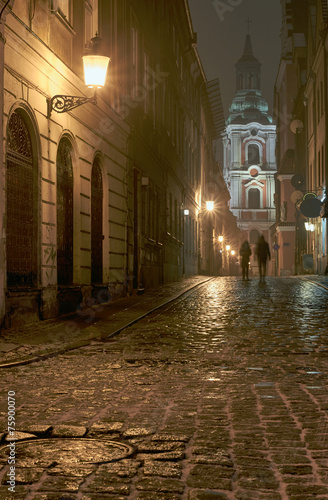 Melting snow on the cobbled street at night in Poznan.