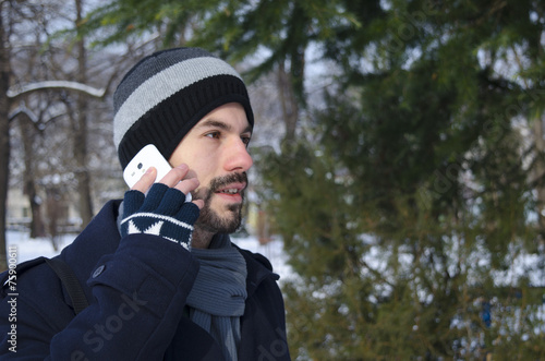 Young man talking on a smartphone in winter time