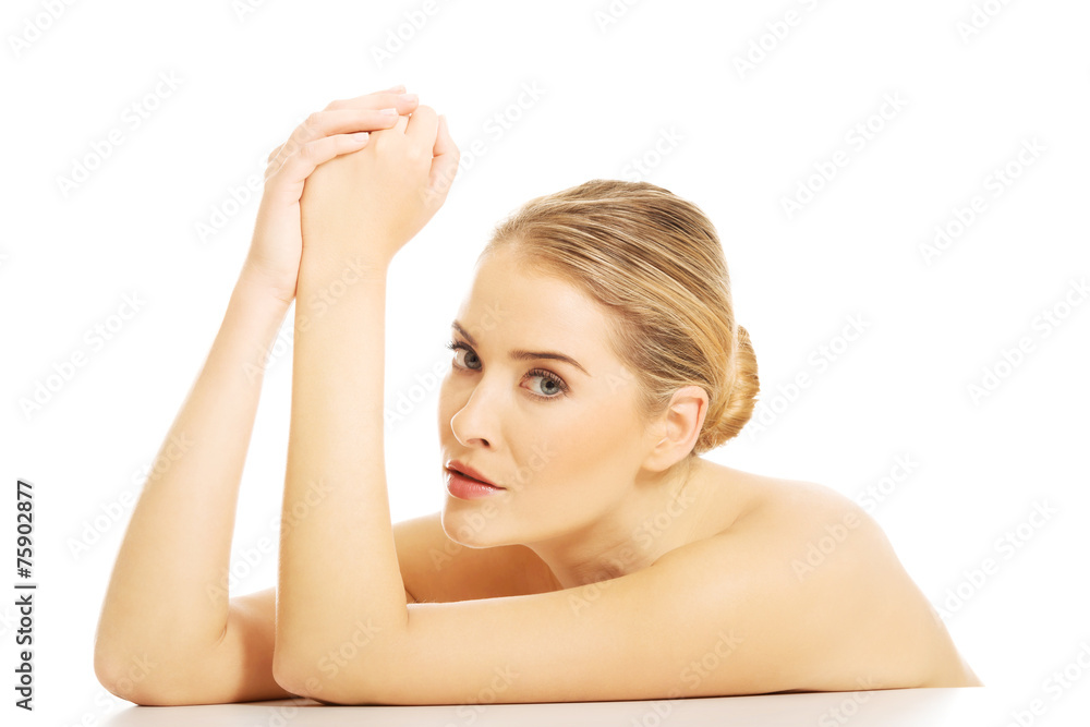 Portrait of nude woman clenching hands, sitting at the desk