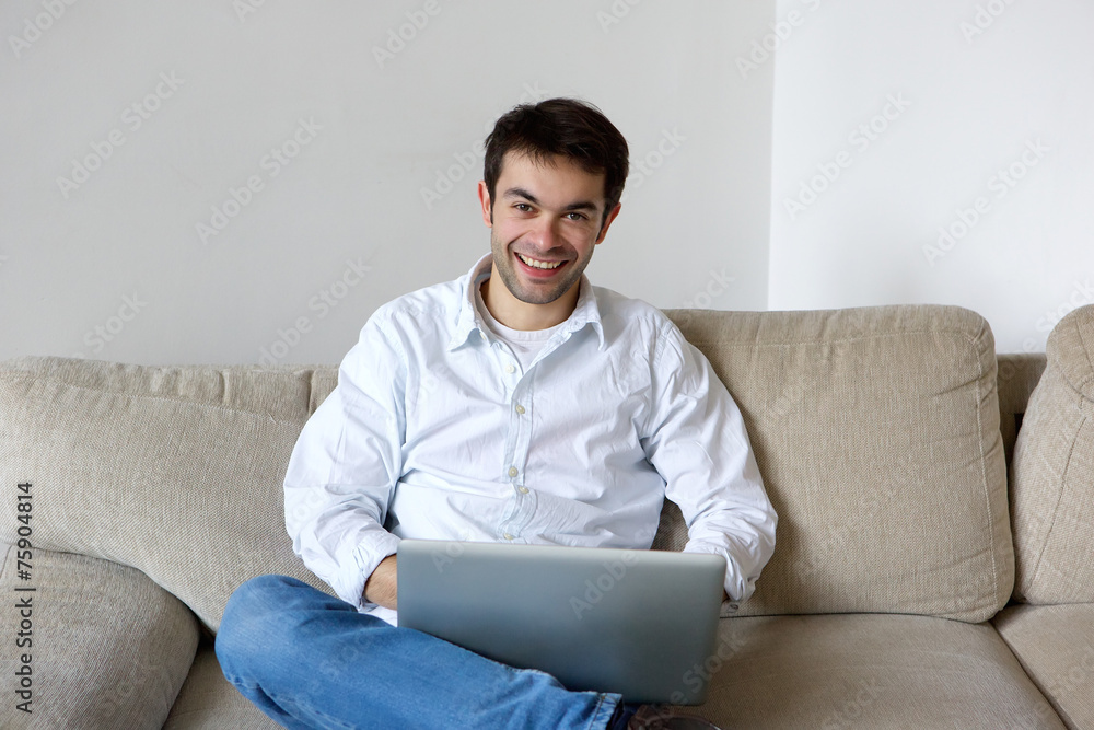 Smiling young man using laptop at home Smiling young man using laptop at home