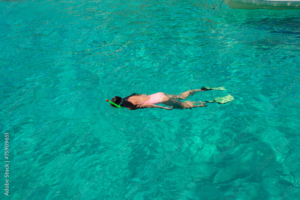 Beautiful girl snorkeling in clear tropical turquoise waters
