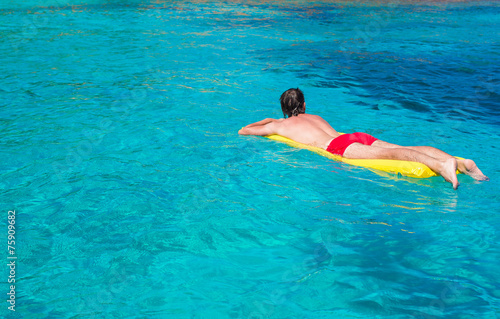 Young man relaxing on inflatable mattress in the sea