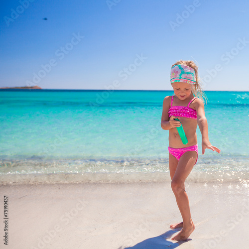 Little adorable girl in swimsuit with suntan lotion bottle © travnikovstudio
