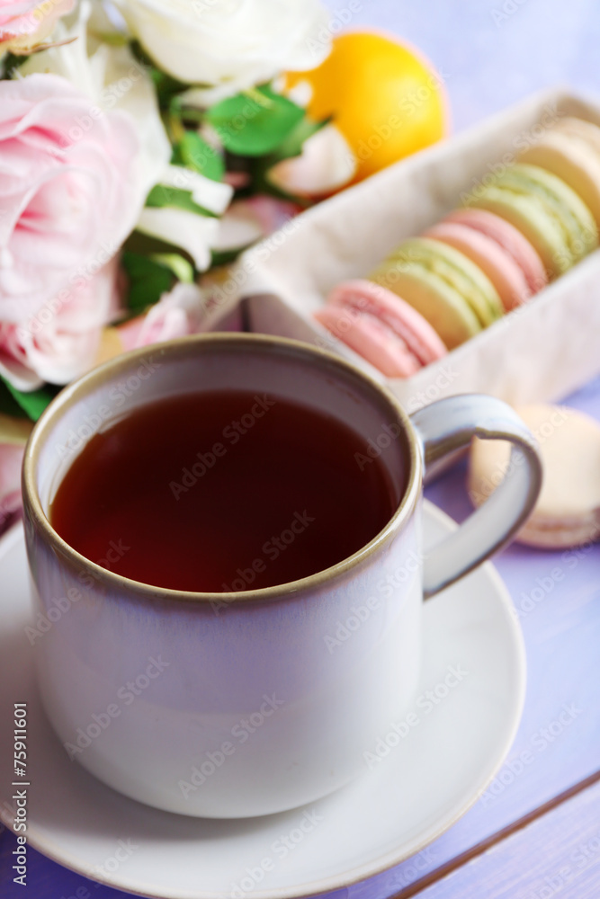Colorful macaroons with cup of tea on wooden background Colorful macaroons with cup of tea on wooden background