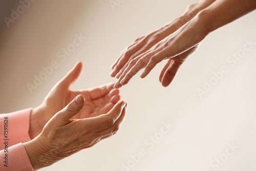Old and young holding hands on light background  closeup