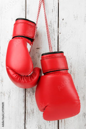 Pair of boxing gloves on color wooden background © Africa Studio