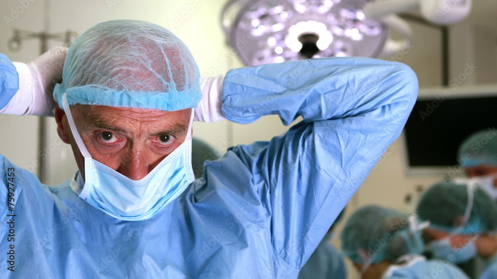 Medical professor in surgical gear putting on mask Medical professor in surgical gear putting on mask