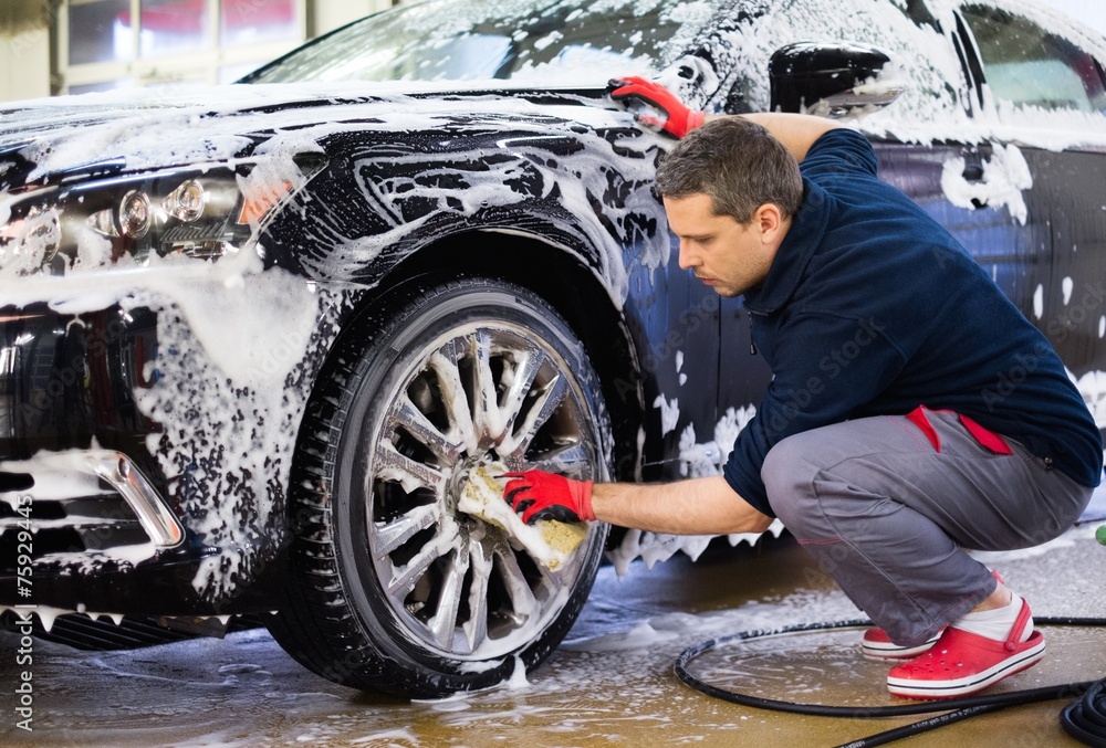 Man worker washing car's alloy wheels on a car wash - obrazy, fototapety, plakaty 