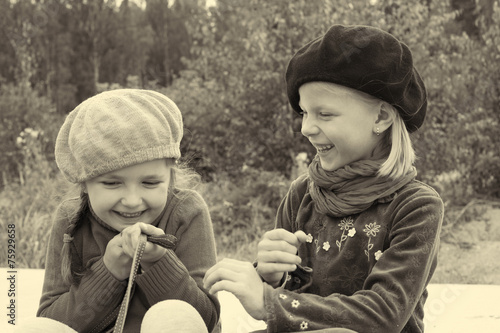 Girls tell each other secrets, sitting at the bus stop
