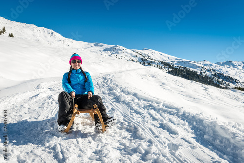 Smiling girl on a sledge in the snow