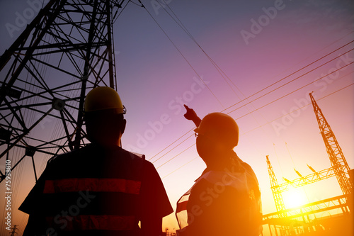 two worker watching the power tower and substation with sunset b photo