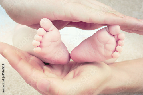 Baby´s feet surrounded by fathers strong hands.