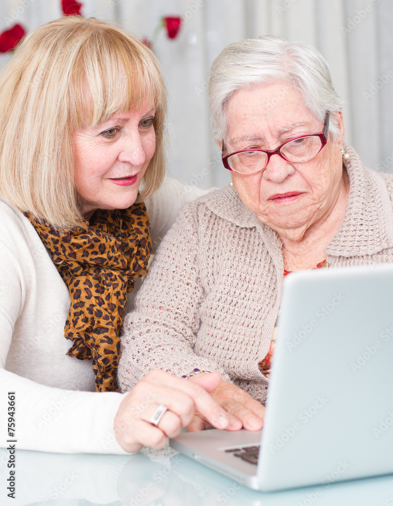 Daughter teaches her elderly mother using a computer Daughter teaches her elderly mother using a computer