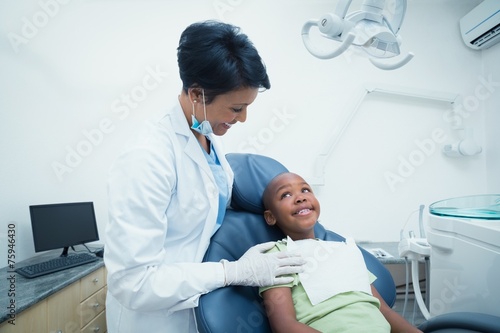 Smiling female dentist examining boys teeth