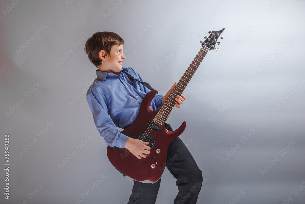 boy teenager European appearance playing guitar on a gray backgr boy teenager European appearance playing guitar on a gray backgr