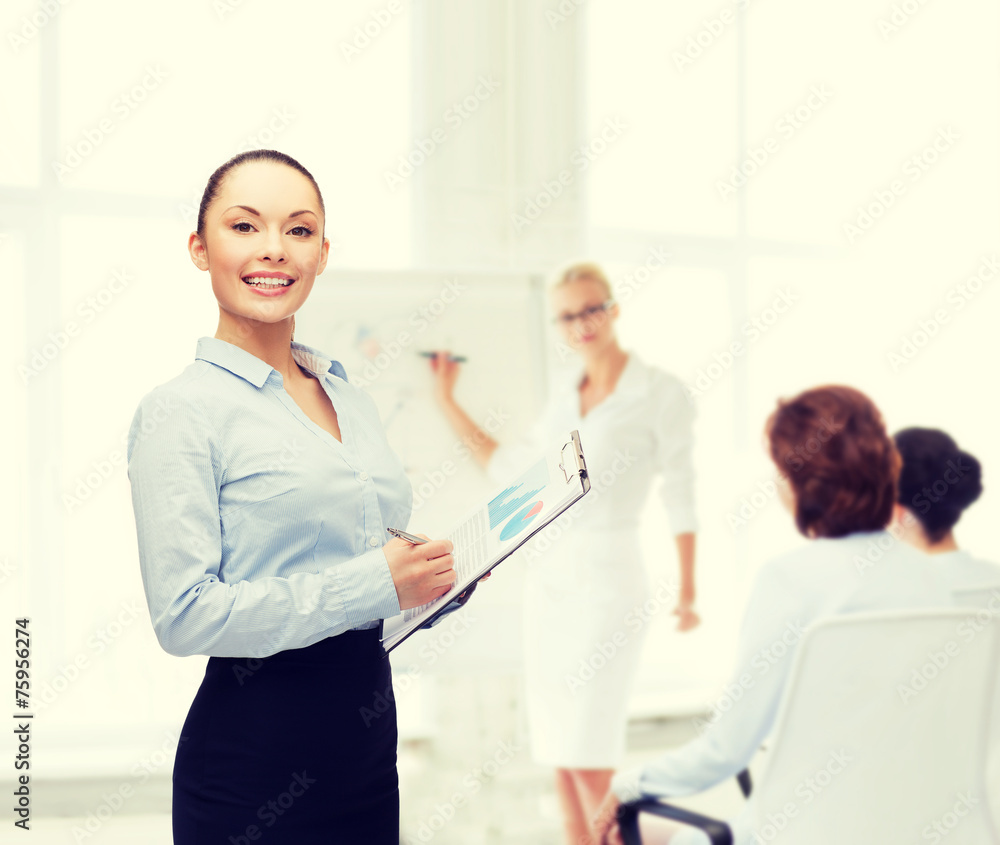 Fototapeta premium young smiling businesswoman with clipboard and pen