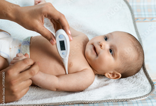 mother measures the temperature of smiling child