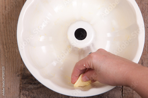 Canvas Print Greasing cake pan with margarine or butter.