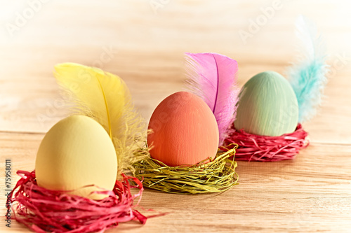 Painted Easter Eggs in colorful nests on wooden background