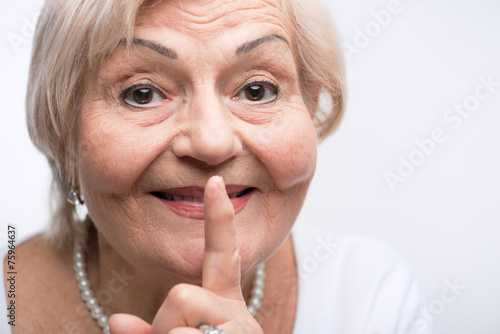 Elderly lady putting finger on her mouth
