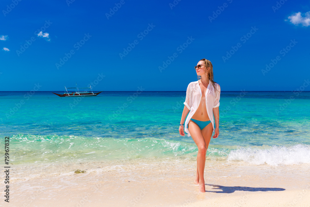 Young beautiful girl in wet white shirt  on the beach. Blue trop