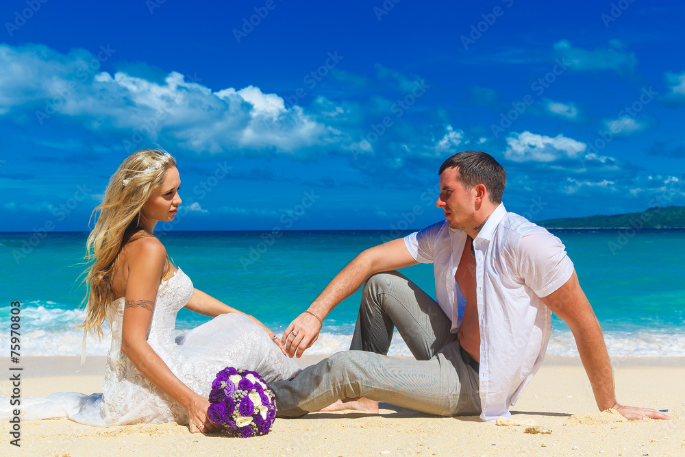 bride and groom on a tropical beach. wedding bouquet in the fore