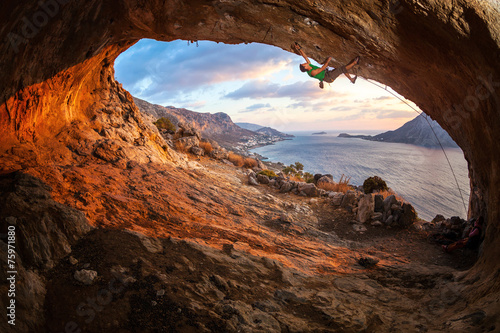 Young man lead climbing in cave before sunset