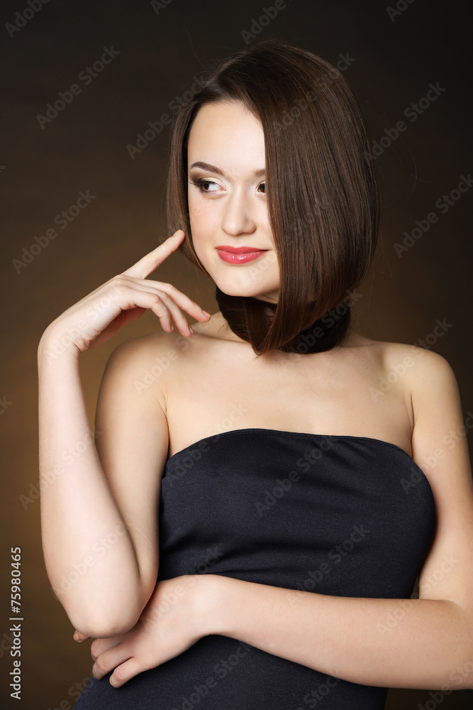 Beautiful young woman with long hair on dark brown background