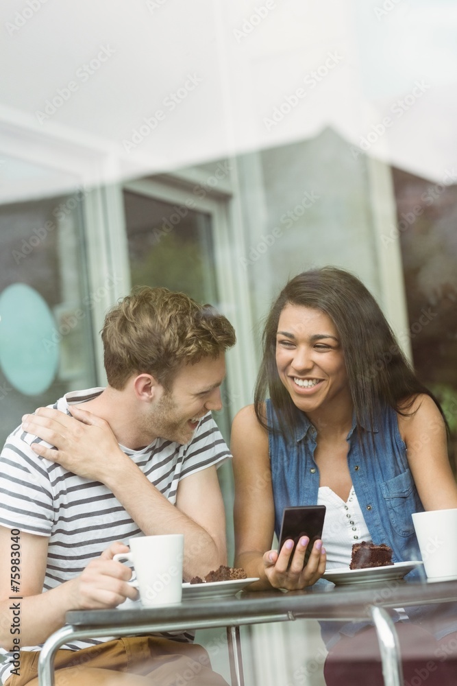 Smiling friends with chocolate cake using smartphone Smiling friends with chocolate cake using smartphone