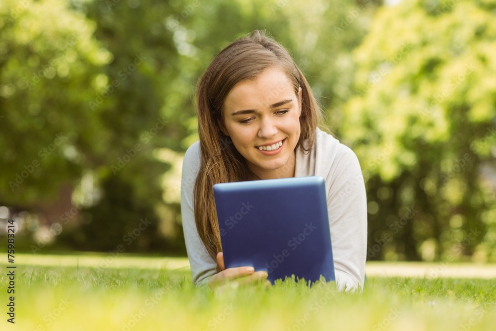 Smiling university student lying and using tablet pc Smiling university student lying and using tablet pc