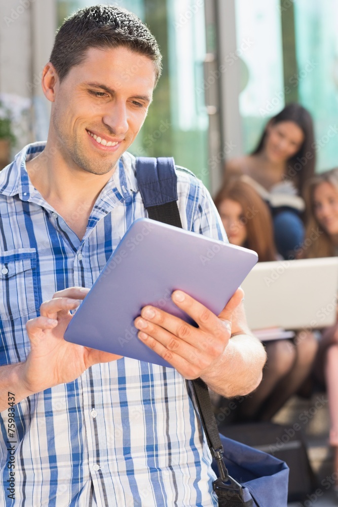 Happy student using his tablet pc on campus Happy student using his tablet pc on campus