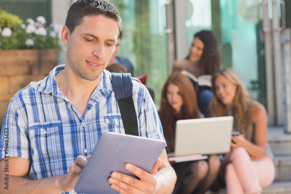 Happy student using his tablet pc on campus Happy student using his tablet pc on campus