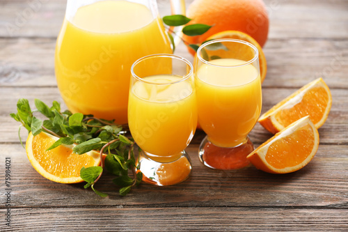 Glass of orange juice and slices on wooden table background