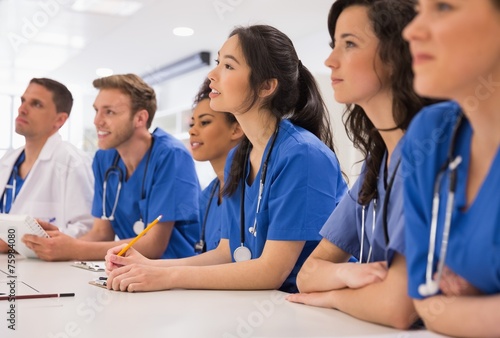 Medical students listening sitting at desk