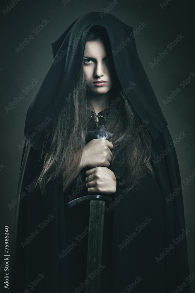 Foto de Beautiful dark woman with black robe and sword do Stock