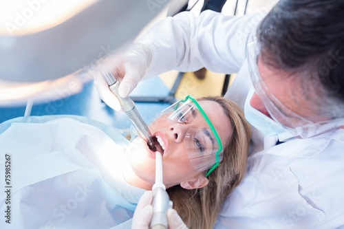 Dentist examining his patient with a suction hose