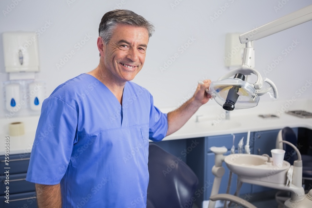 Portrait of a friendly dentist holding light - obrazy, fototapety, plakaty 