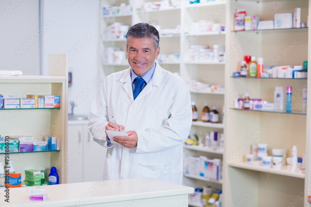 Portrait of a smiling pharmacist writing down notes