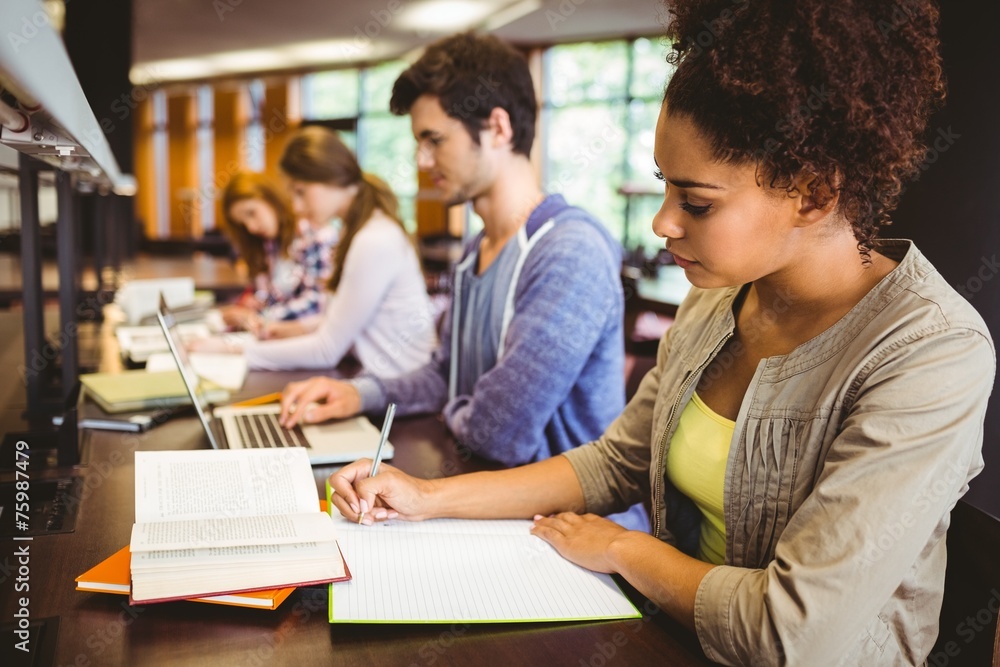 Focused students sitting in a line writing Focused students sitting in a line writing