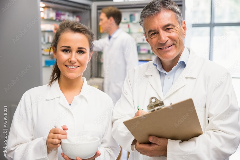 Fototapeta premium Junior pharmacist mixing a medicine with her senior