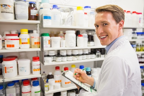 Handsome pharmacist writing on clipboard