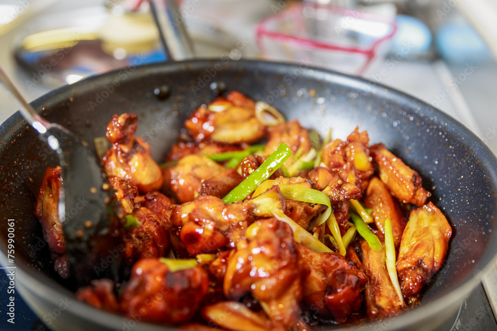 Asian caramelized chicken wings cooking into a wok Asian caramelized chicken wings cooking into a wok
